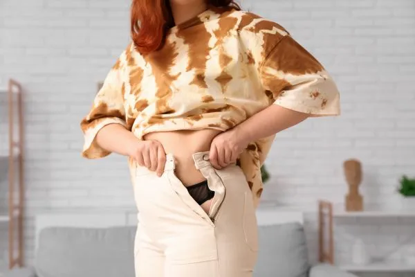 Image of woman trying to do her trousers up after pregnancy weight gain Sutton Coldfield